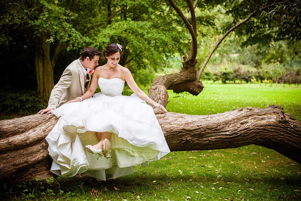 brooksby wedding photographer bride sitting on a branch while groom kisses her shoulder, brooksby wedding photographer